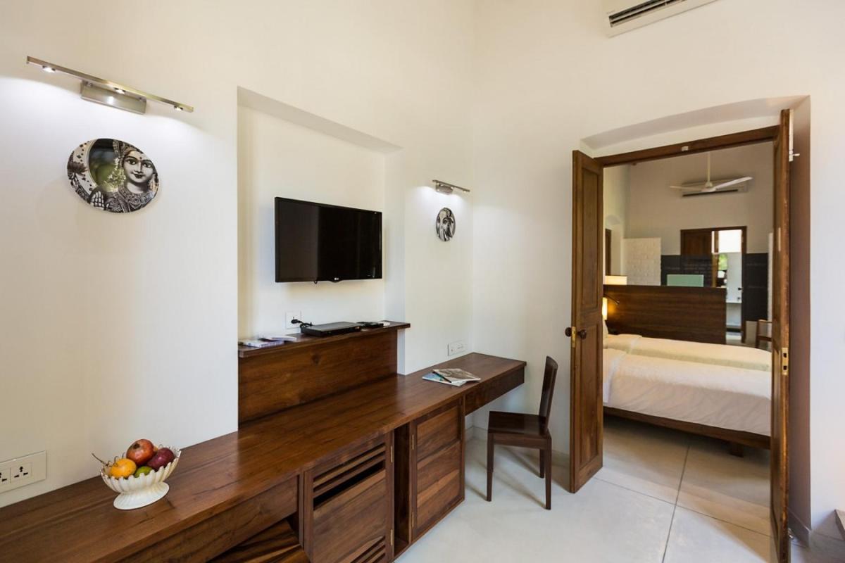 a hotel room with a desk and a bed at La Villa in Puducherry