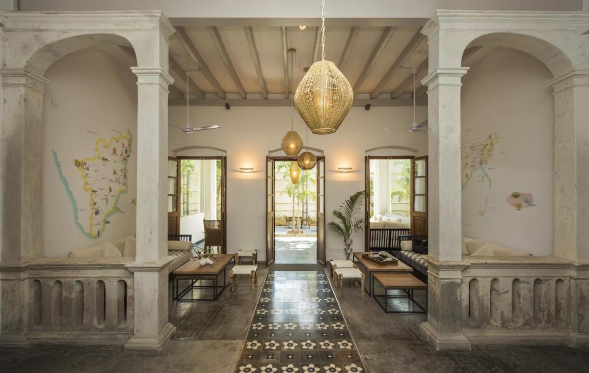 a lobby with tables and chairs in a building at La Villa in Puducherry