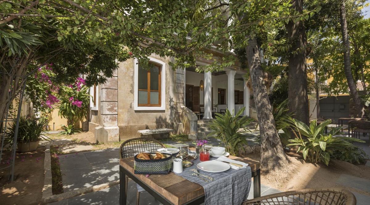 a table with food on it in front of a house at La Villa in Puducherry