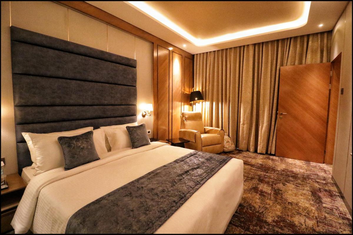 a hotel room with a large bed and a chair at Sayaji Pune in Pune