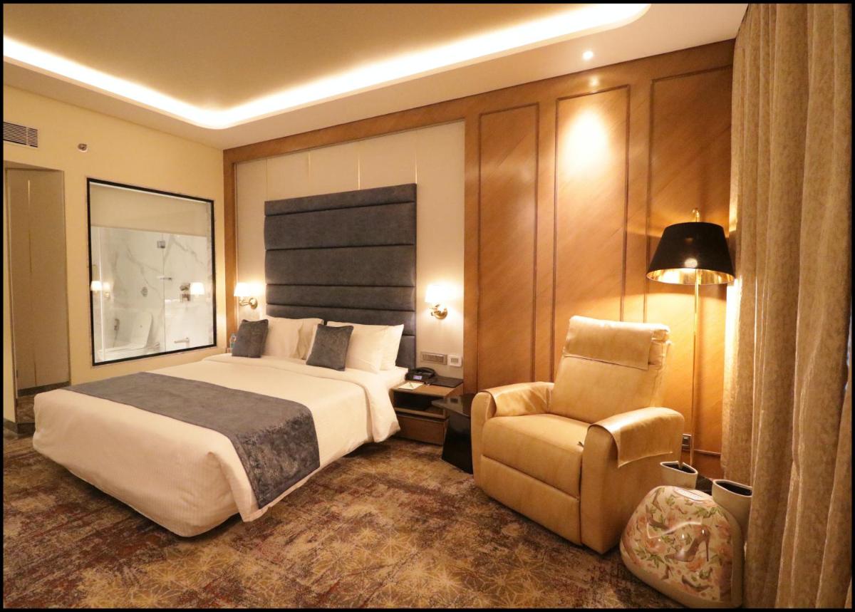 a hotel room with a bed and a chair at Sayaji Pune in Pune