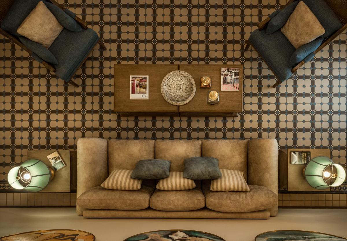 a living room with a brown couch and some plates at MansionHaus in Anjuna
