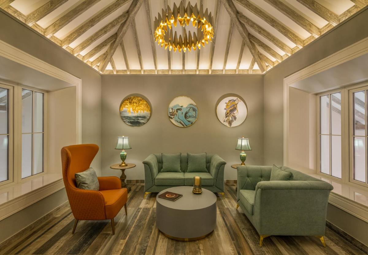 a living room with couches and chairs and a chandelier at MansionHaus in Anjuna