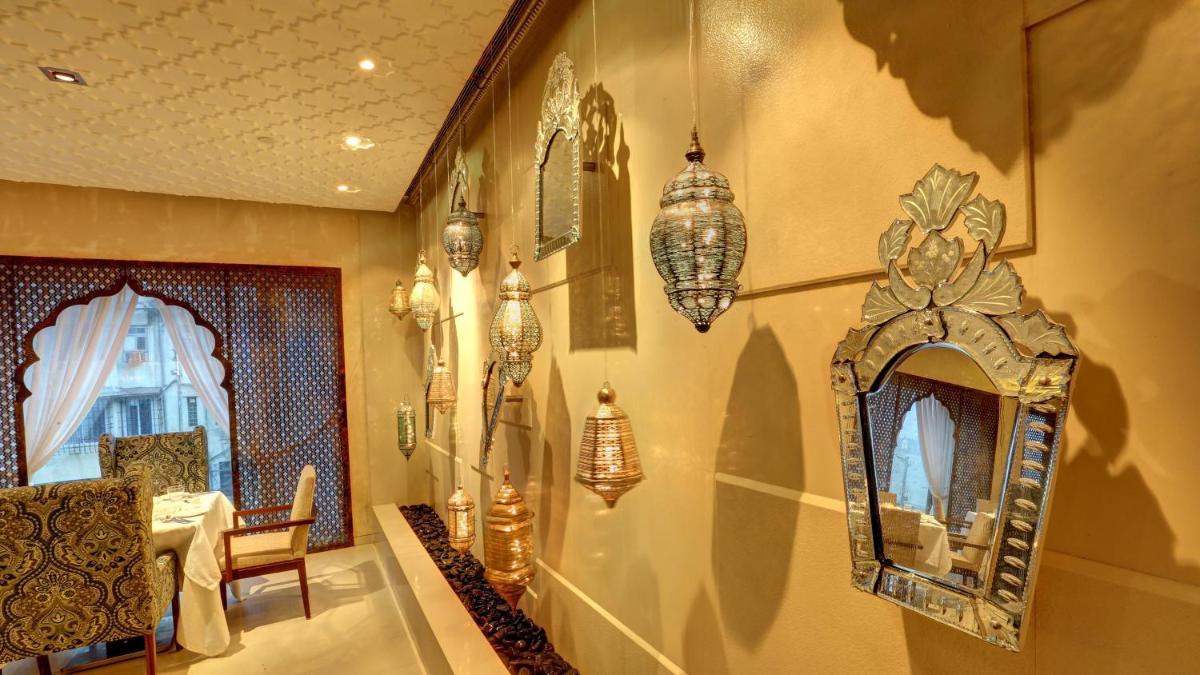 a dining room with a mirror and chandeliers on the wall at InterContinental Marine Drive Mumbai by IHG in Mumbai