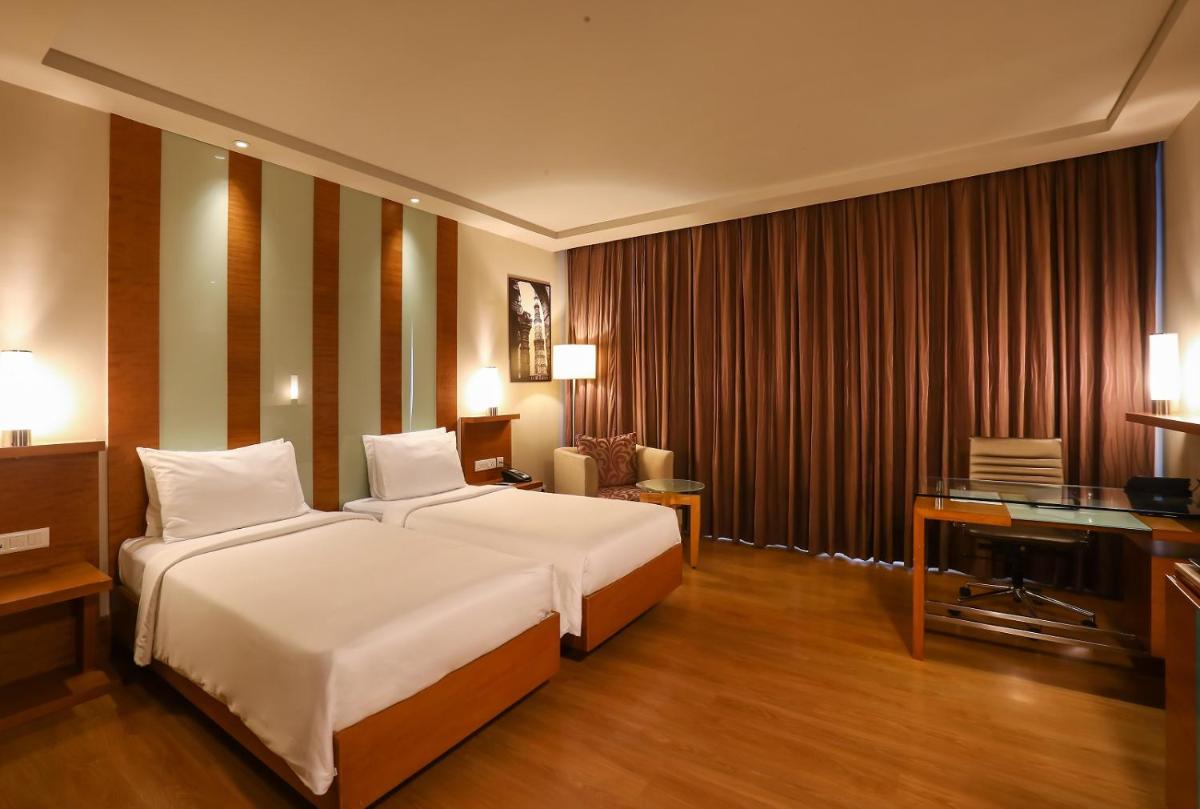 a bedroom with a large white bed and a desk at Radisson Blu Hotel Chennai City Centre in Chennai a bedroom with a large white bed and a desk at Radisson Blu Hotel Chennai City Centre in Chennai