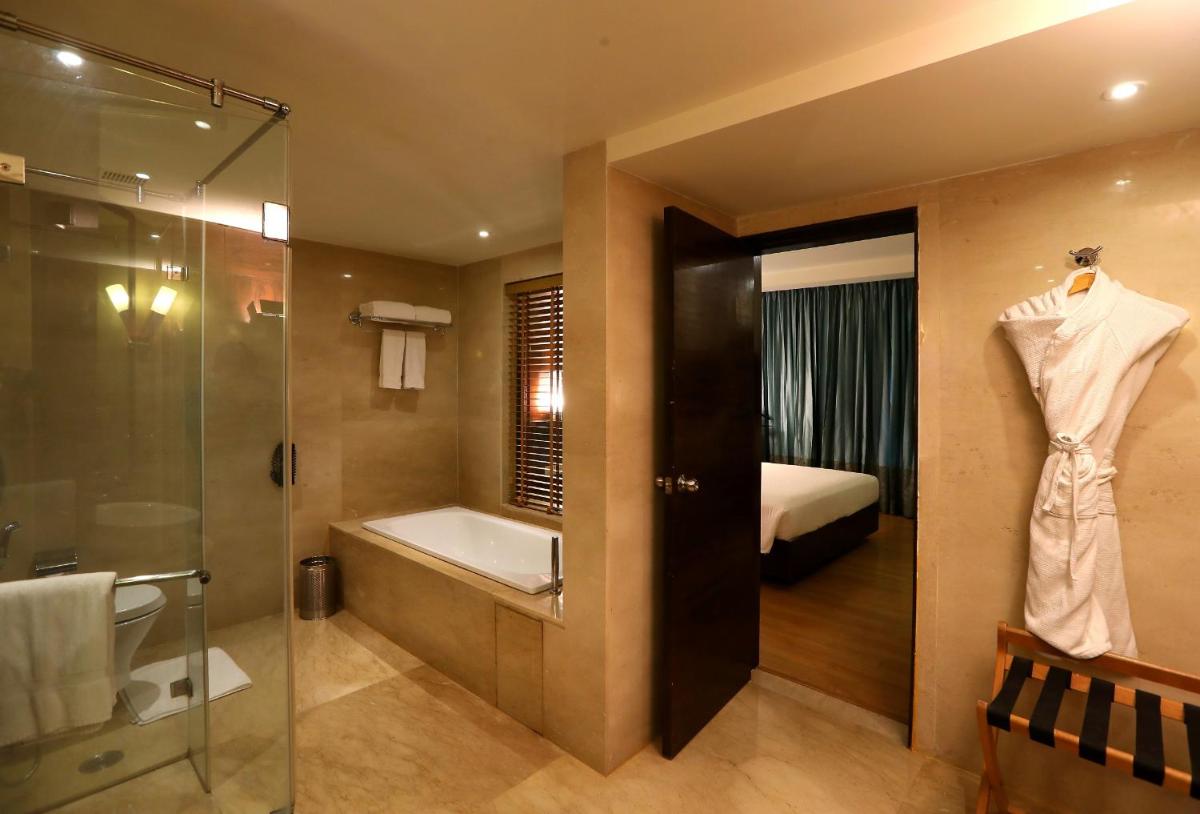 a bathroom with a shower and a bath tub and a bed at Radisson Blu Hotel Chennai City Centre in Chennai a bathroom with a shower and a bath tub and a bed at Radisson Blu Hotel Chennai City Centre in Chennai
