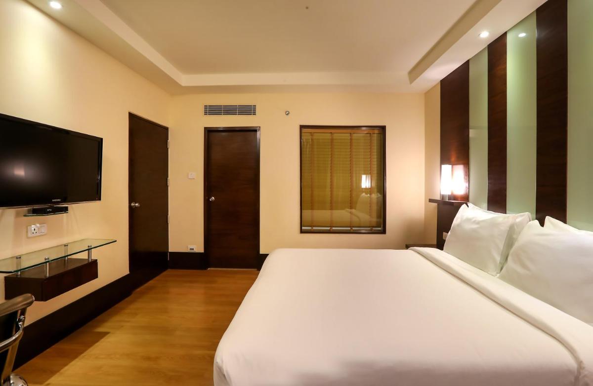 a bedroom with a large white bed and a television at Radisson Blu Hotel Chennai City Centre in Chennai a bedroom with a large white bed and a television at Radisson Blu Hotel Chennai City Centre in Chennai