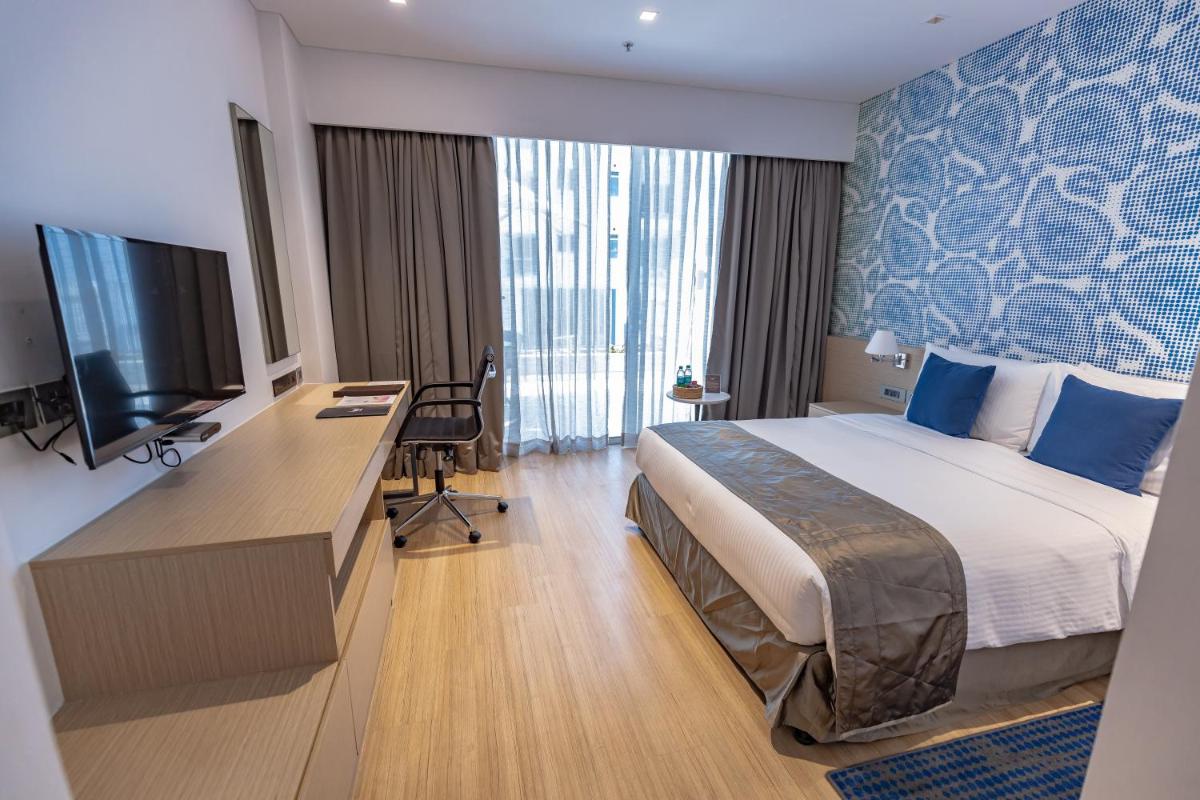 a hotel room with a bed and a desk and a television at Citadines OMR Chennai in Chennai a hotel room with a bed and a desk and a television at Citadines OMR Chennai in Chennai