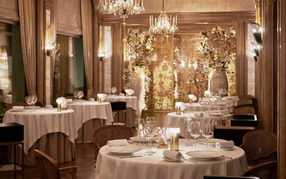 un restaurant avec des tables et des chaises blanches et des lustres dans l'établissement La Réserve de Beaulieu, à Beaulieu-sur-Mer 112 autres photos