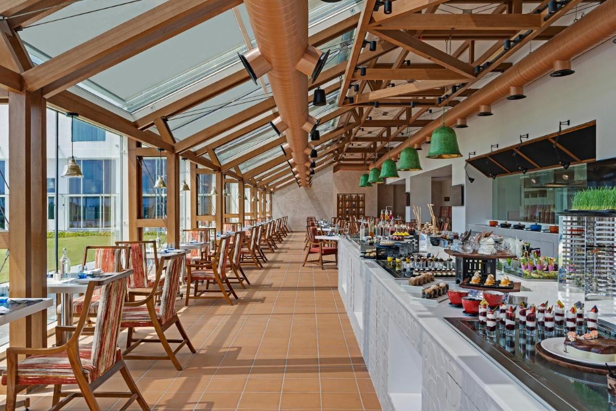 a restaurant with tables and chairs and windows at O by Tamara, Trivandrum in Trivandrum