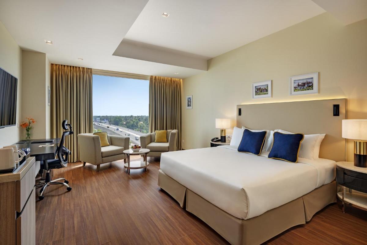 a hotel room with a large bed and a television at O by Tamara, Trivandrum in Trivandrum