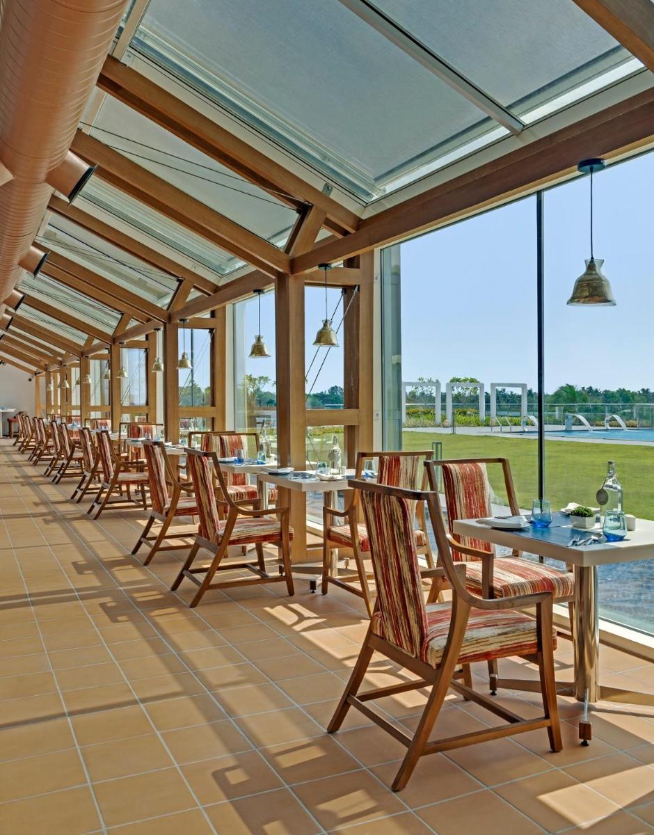 a row of tables and chairs in a room with windows at O by Tamara, Trivandrum in Trivandrum