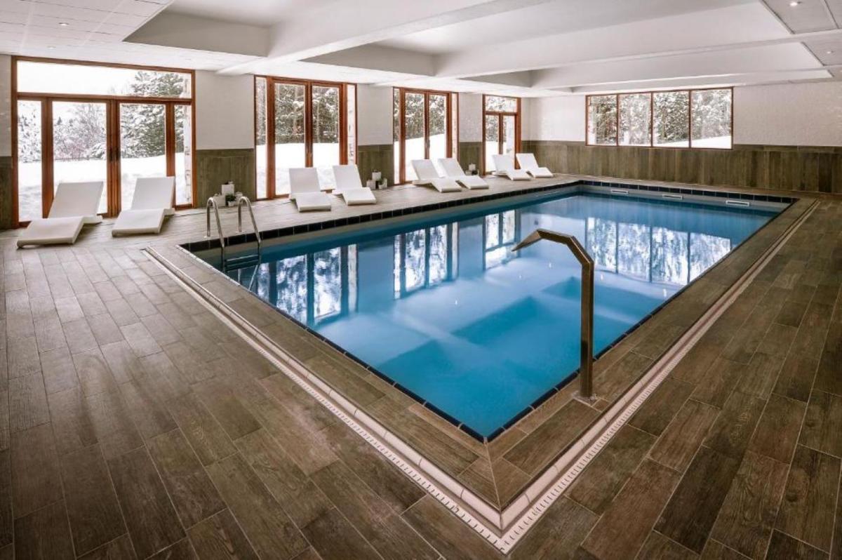 - une grande piscine avec des chaises blanches dans un bâtiment dans l'établissement Le Pic Blanc, à L'Alpe-d'Huez