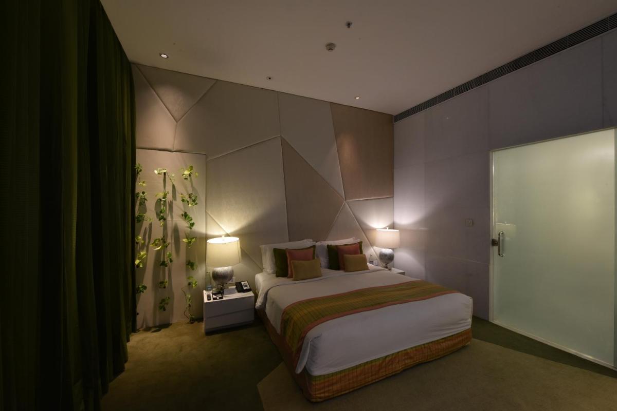 a bedroom with a large bed and two lamps at Vivanta New Delhi, Dwarka in New Delhi a bedroom with a large bed and two lamps at Vivanta New Delhi, Dwarka in New Delhi