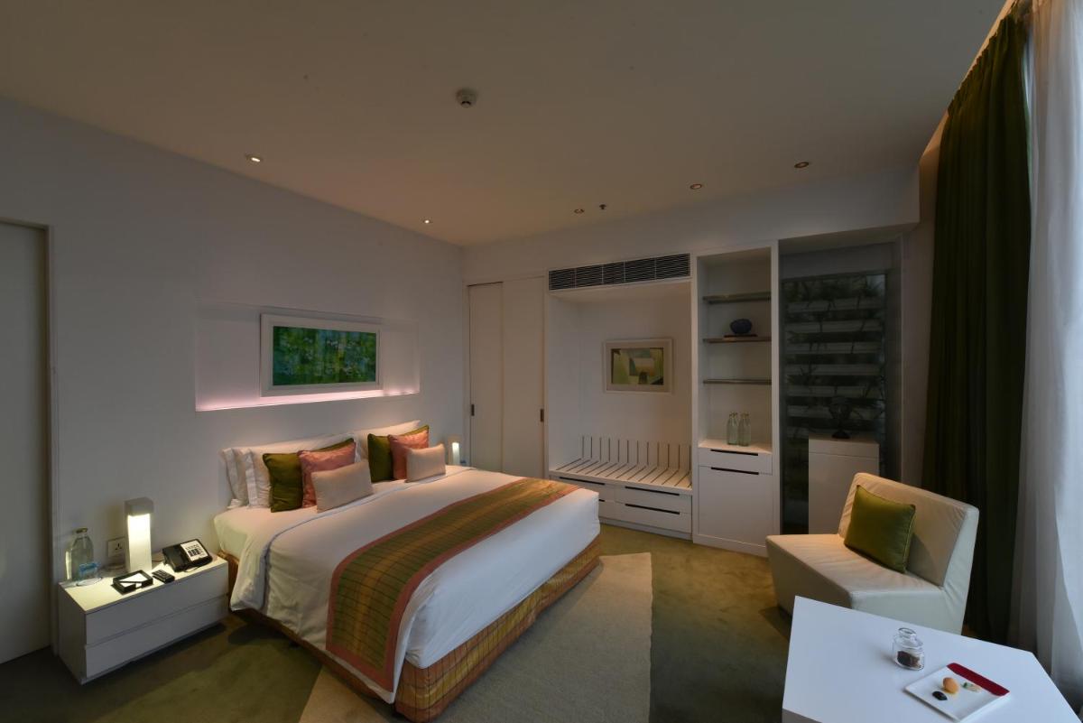 a bedroom with a large white bed and a chair at Vivanta New Delhi, Dwarka in New Delhi a bedroom with a large white bed and a chair at Vivanta New Delhi, Dwarka in New Delhi