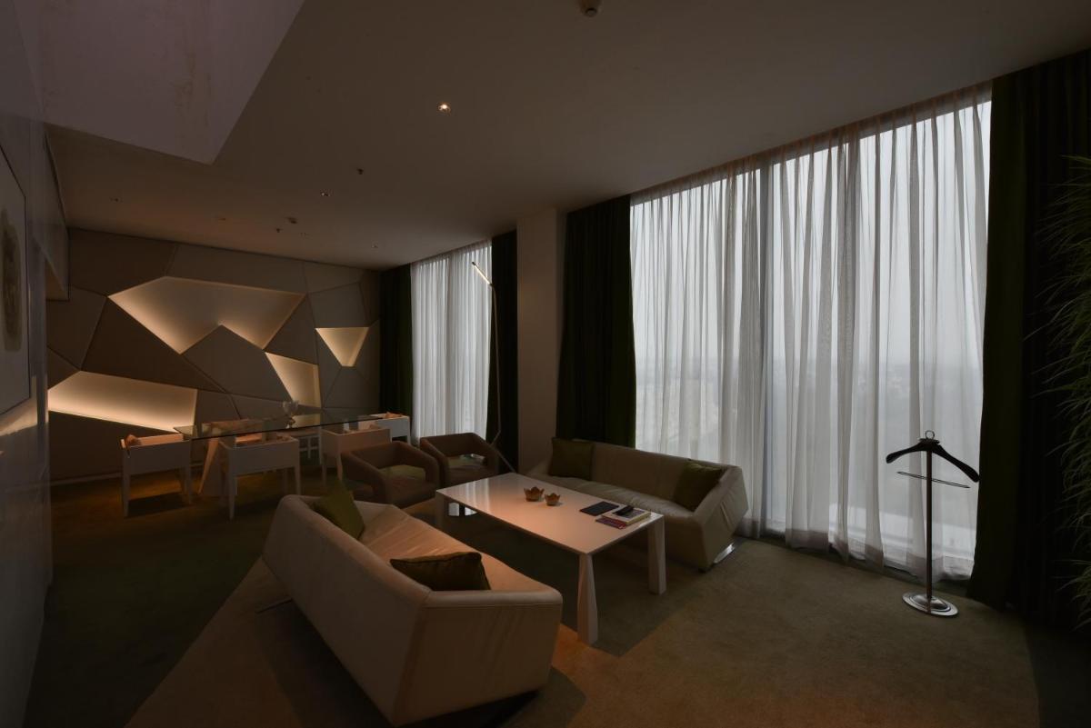 a living room with furniture and a large window at Vivanta New Delhi, Dwarka in New Delhi a living room with furniture and a large window at Vivanta New Delhi, Dwarka in New Delhi
