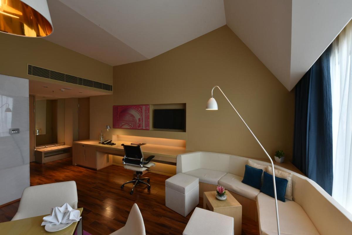 a living room with a white couch and a desk at Vivanta New Delhi, Dwarka in New Delhi a living room with a white couch and a desk at Vivanta New Delhi, Dwarka in New Delhi