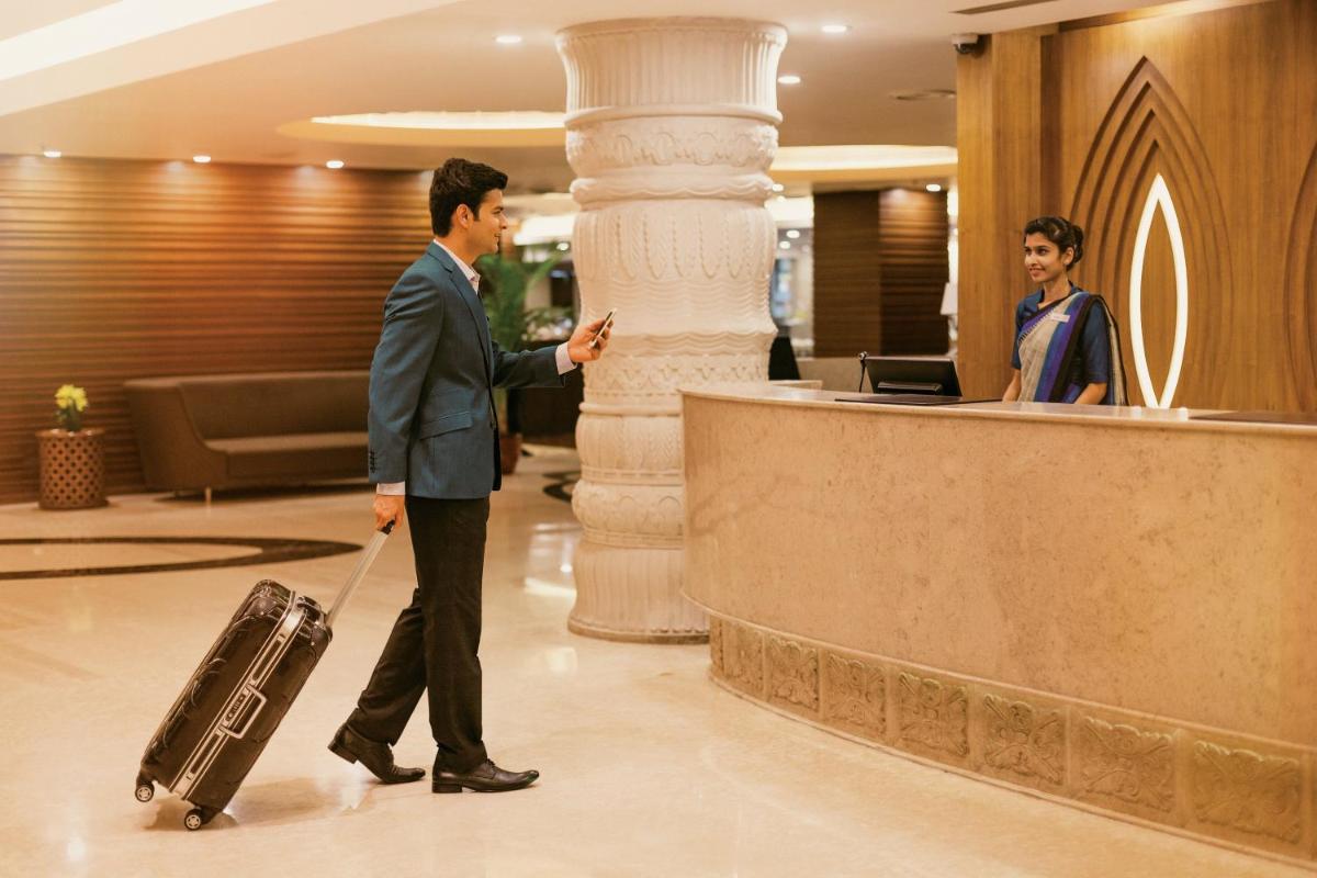 a man with a suitcase in a hotel lobby at Crowne Plaza Ahmedabad City Centre by IHG in Ahmedabad