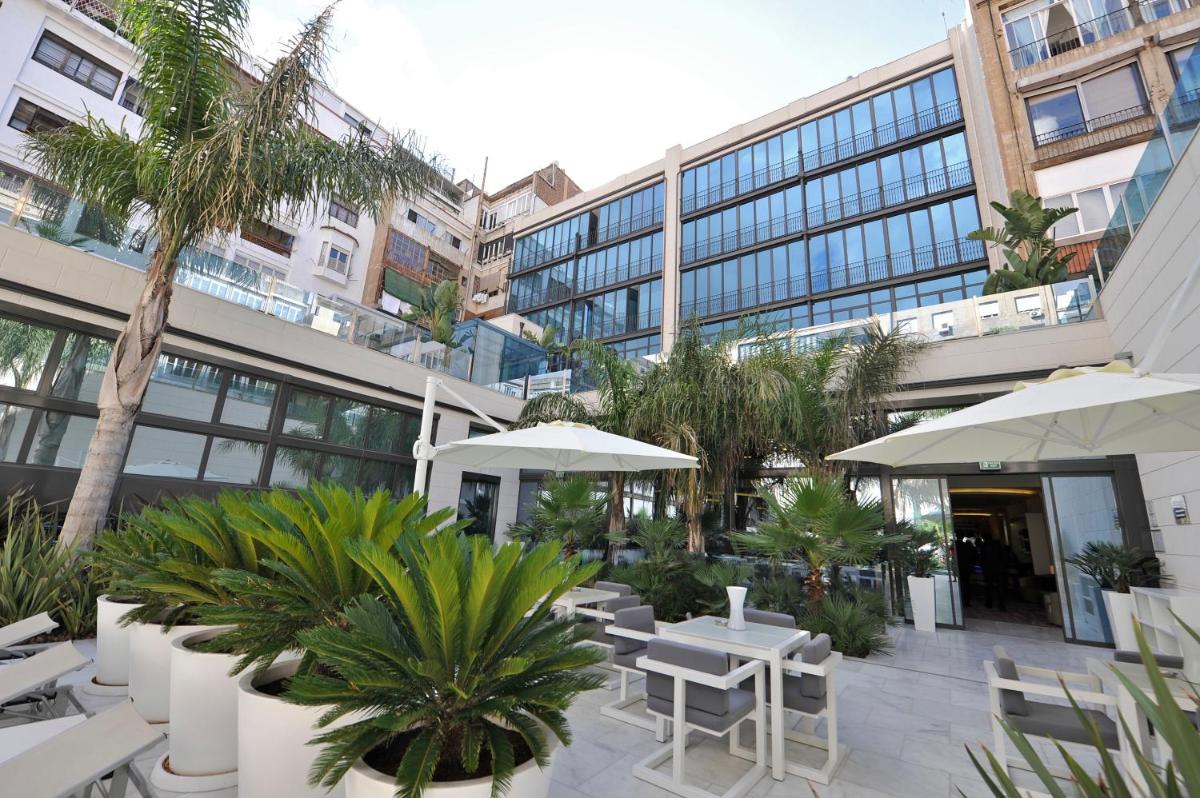 Un patio con mesas y sombrillas frente a un edificio. en Hotel Indigo Barcelona - Plaza Catalunya 4Sup by IHG, en Barcelona