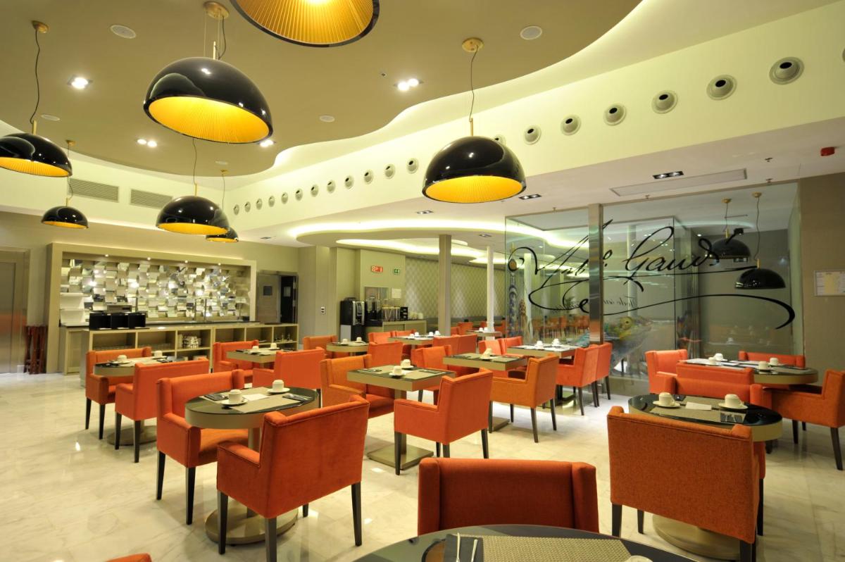 un restaurante con mesas y sillas naranjas en una habitación en Hotel Indigo Barcelona - Plaza Catalunya 4Sup by IHG, en Barcelona