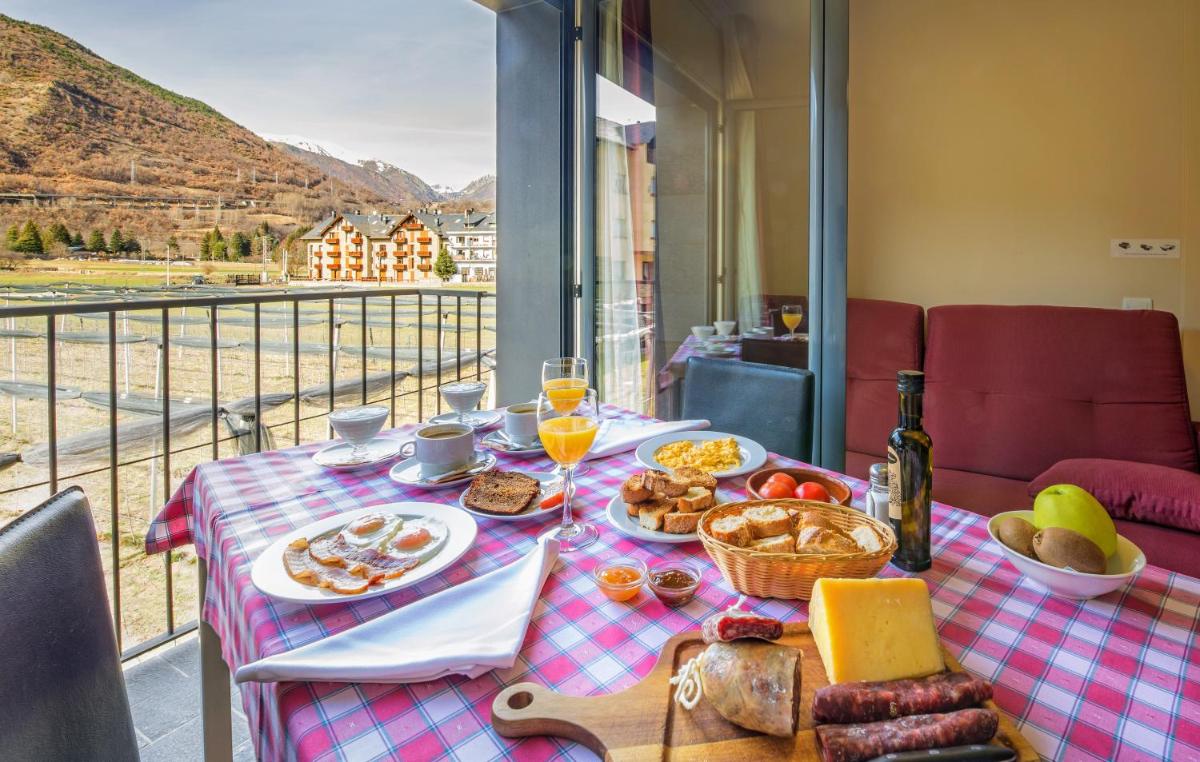 una mesa con comida y bebida y vistas a la montaña en Aparthotel Trainera, en Esterri d'Àneu