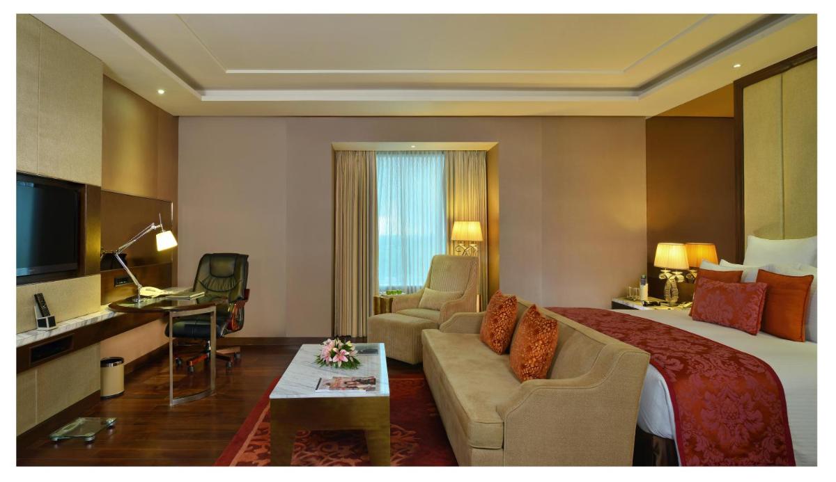 a hotel room with a bed and a living room at Radisson Blu Jaipur in Jaipur