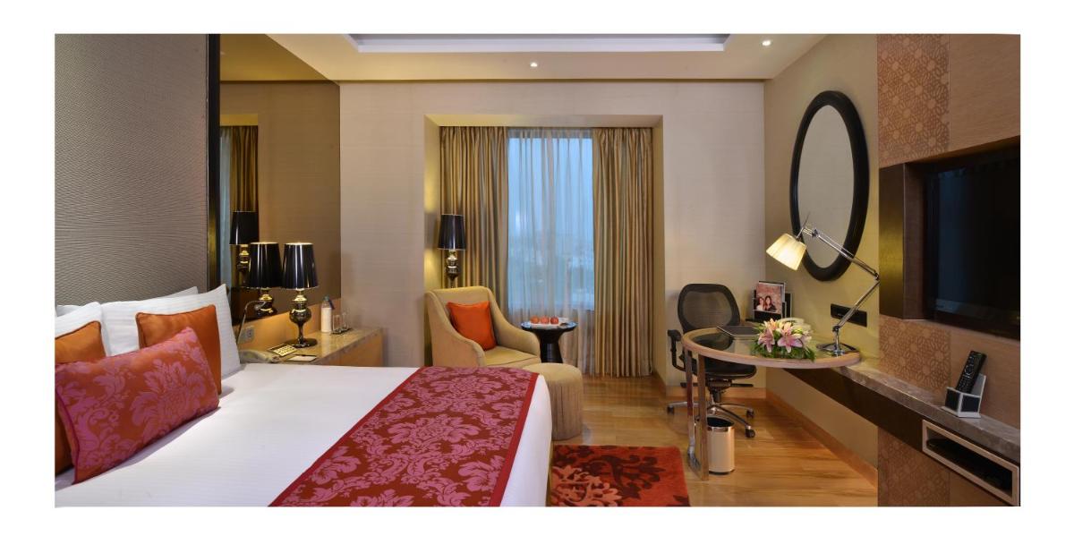 a hotel room with a large bed and a mirror at Radisson Blu Jaipur in Jaipur