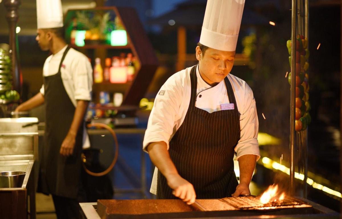 two chefs preparing food in a restaurant kitchen at Crowne Plaza Kochi by IHG in Cochin