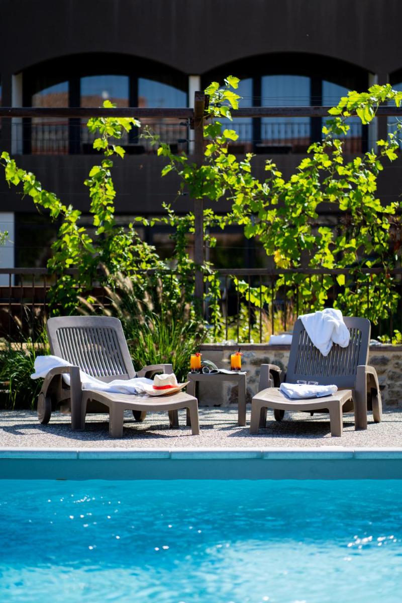 deux chaises assises à côté d'une piscine dans l'établissement Fac & Spera -Hôtel & Spa, à Tain-lʼHermitage