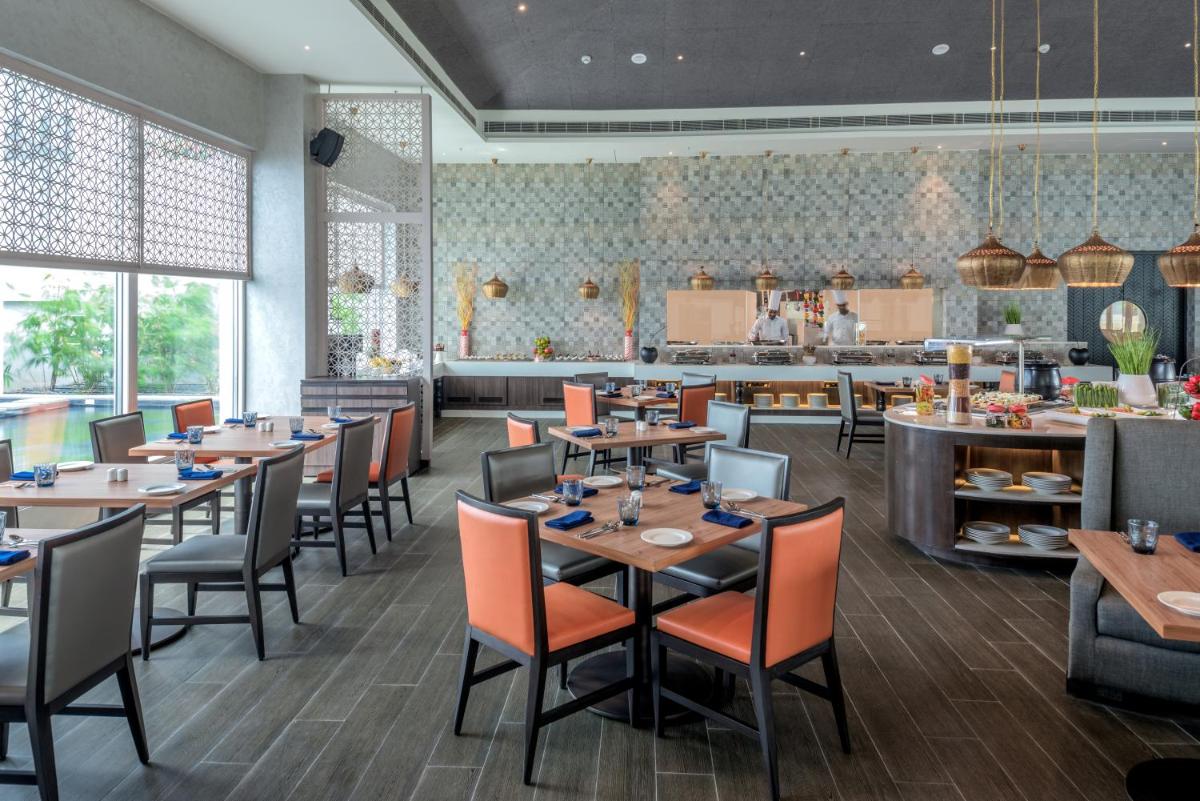 a dining room with tables and chairs and a cafeteria at The Residency Towers, Rameswaram in Rāmeswaram