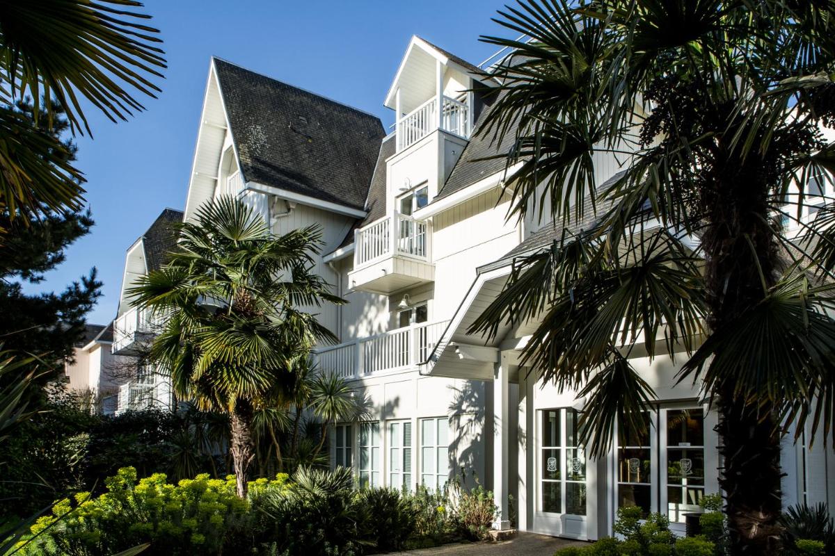 un bâtiment blanc avec des palmiers devant dans l'établissement Emeria Dinard Thalasso Spa, à Dinard