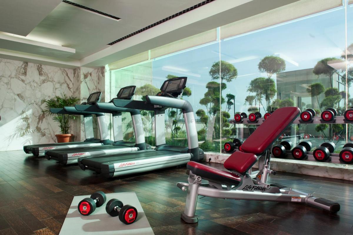 a gym with cardio equipment and a large window at Crowne Plaza New Delhi Okhla by IHG in New Delhi