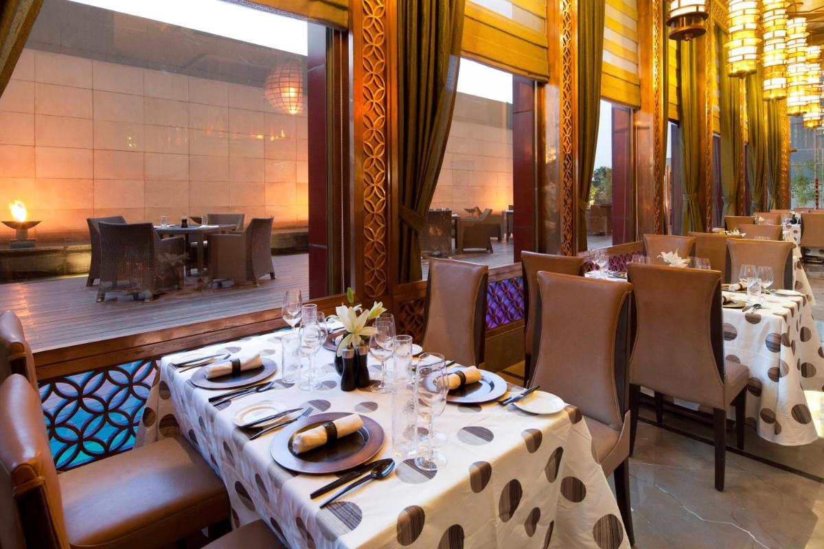 a dining room with tables and chairs in a restaurant at Crowne Plaza New Delhi Okhla by IHG in New Delhi