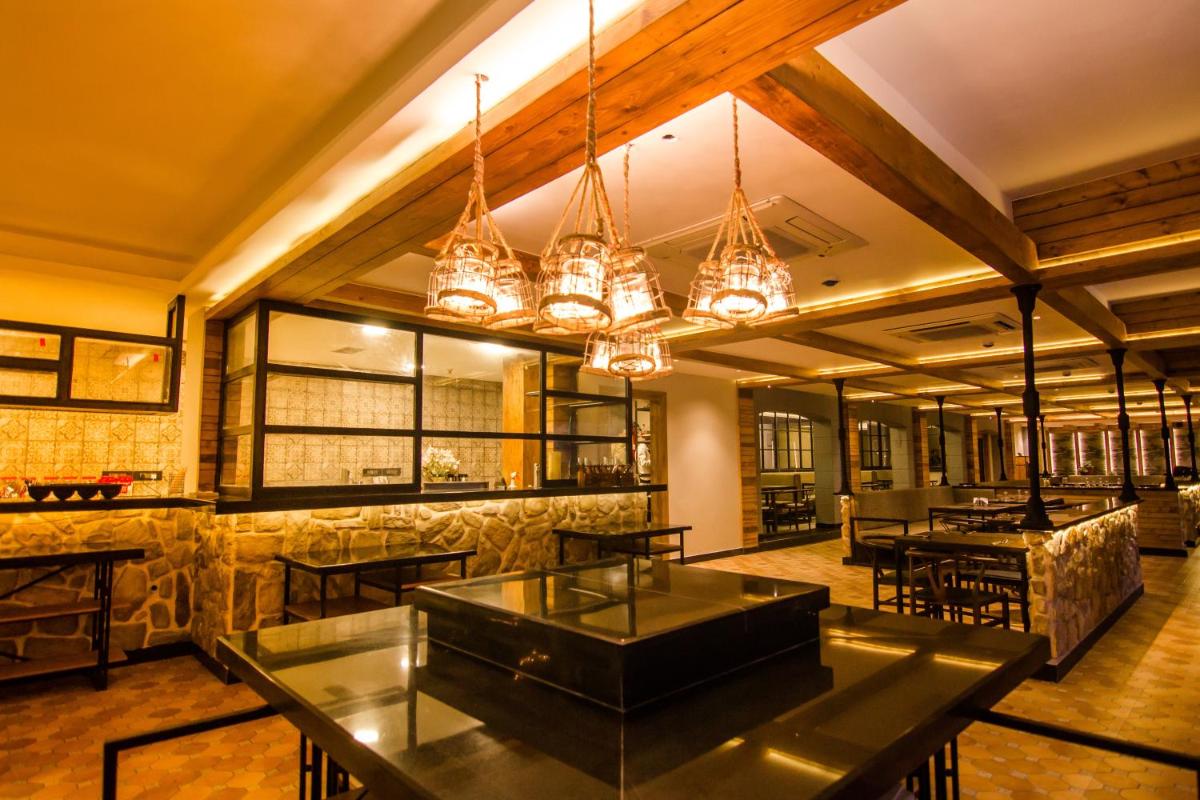 a restaurant with tables and chandeliers in a room at Antalya By Divine Ganga Cottage in Rishīkesh