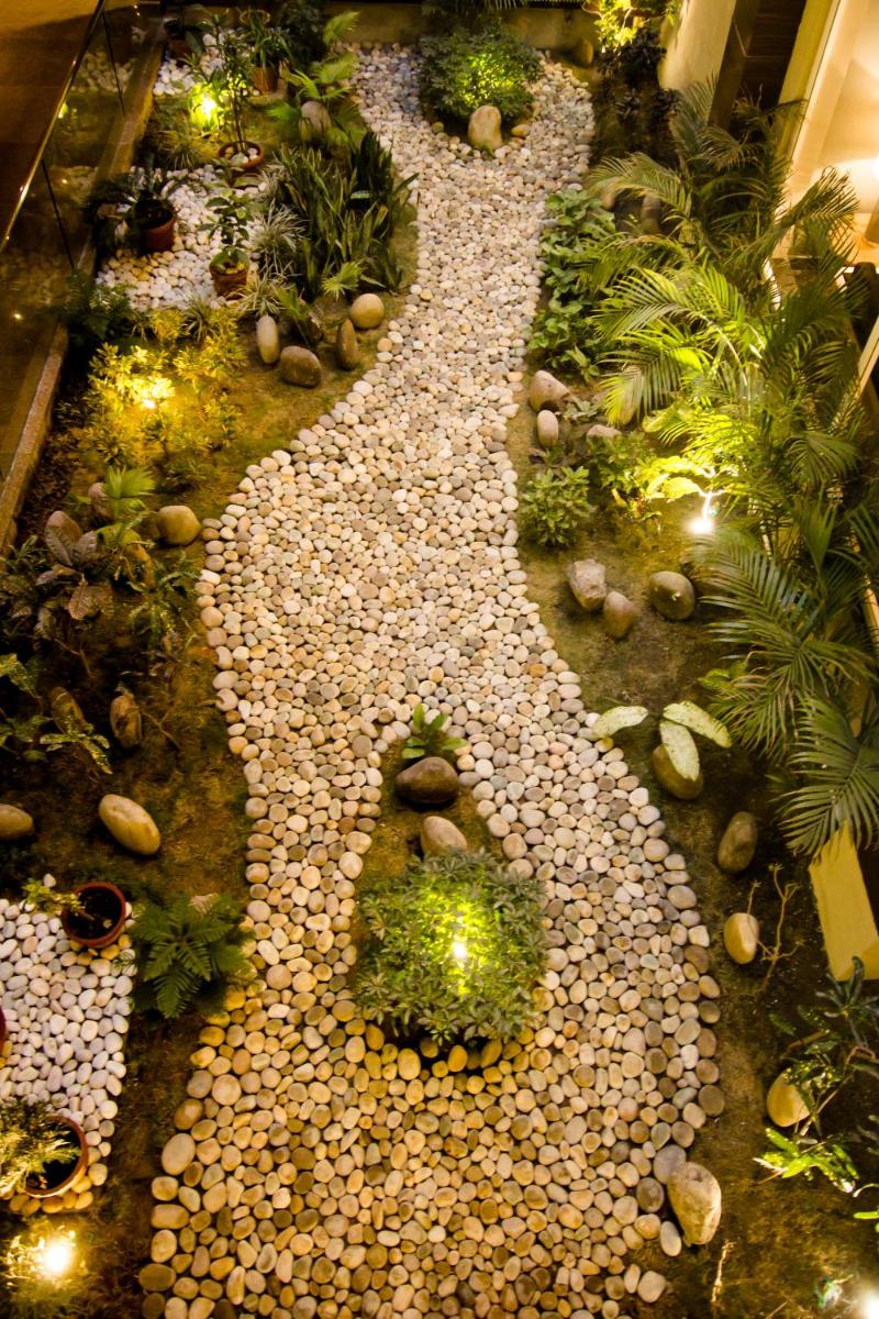 a garden with a gravel pathway with plants and lights at Antalya By Divine Ganga Cottage in Rishīkesh