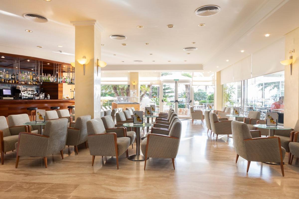 Un comedor con sillas y mesas y ventanas. en Hipotels Dunas Aparthotel, en Cala Millor