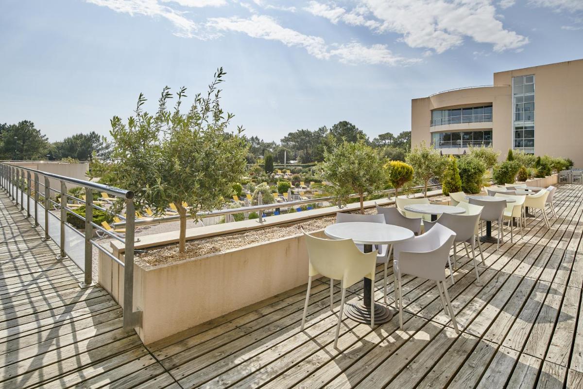 - un balcon avec des tables et des chaises dans un bâtiment dans l'établissement Club Vacances Bleues Les Jardins De l'Atlantique, à Talmont-Saint-Hilaire