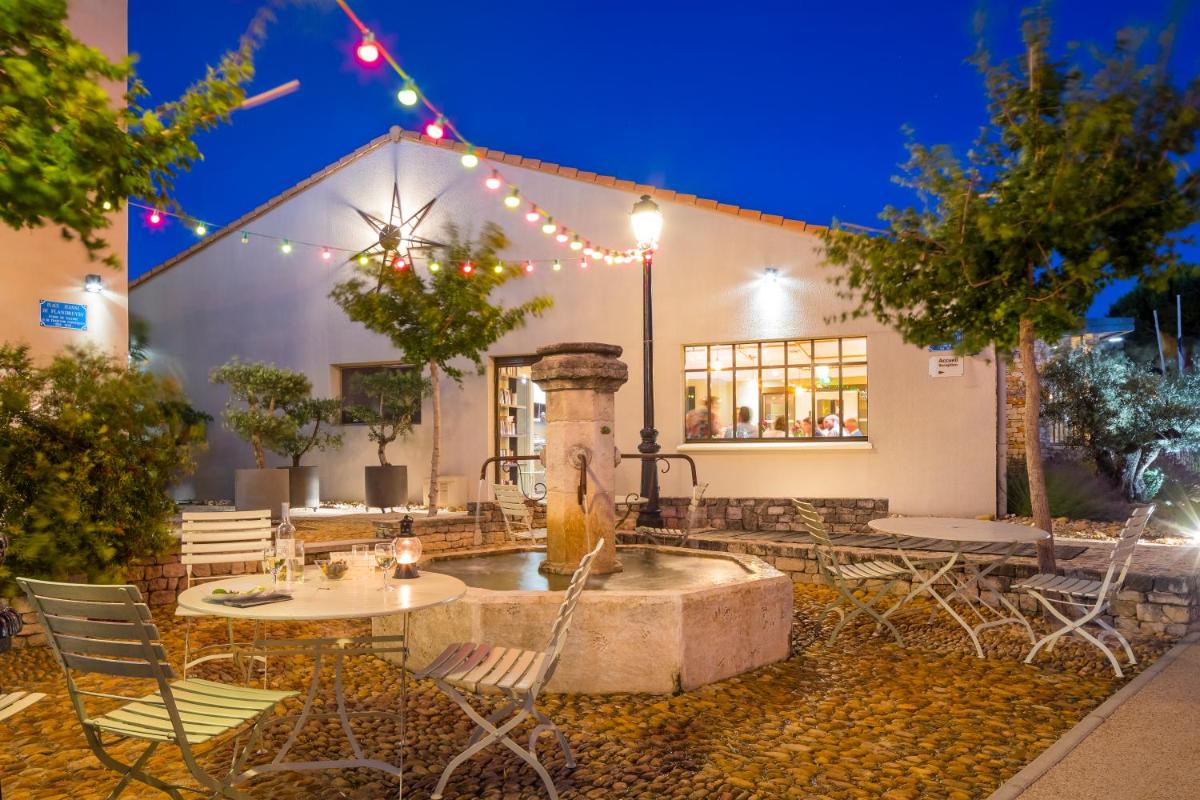 une fontaine devant un bâtiment avec des chaises et des tables dans l'établissement Terre de Provence Hôtel & Spa, au Pontet
