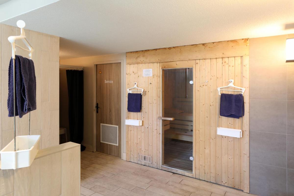 une salle de bain avec des murs en bois, un lavabo et un miroir dans l'établissement SOWELL HOTELS Le Parc & Spa, à Briançon
