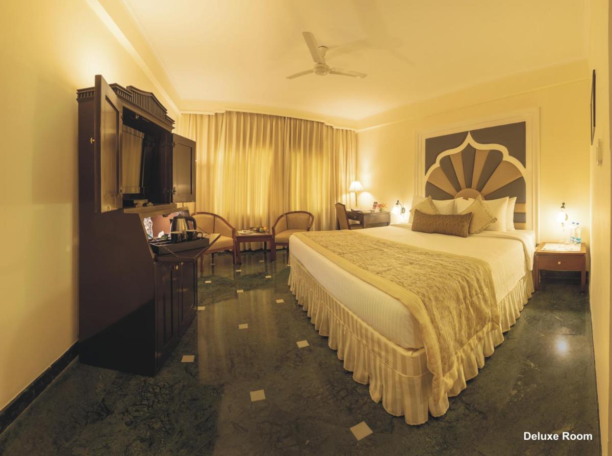 a hotel room with a bed and a flat screen tv at Hotel Clarks Shiraz in Agra