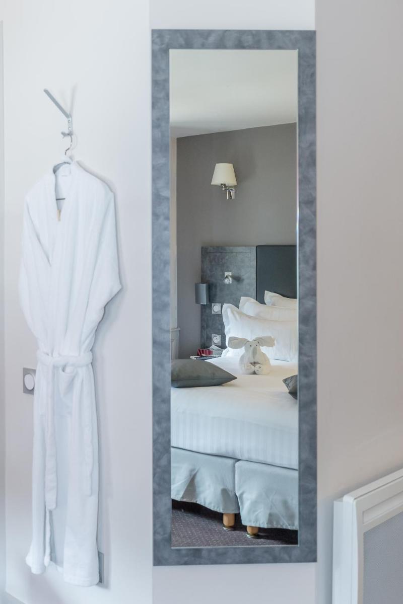 - un miroir dans une chambre avec un lit et un peignoir dans l'établissement La Table de Gustave, à Ornans