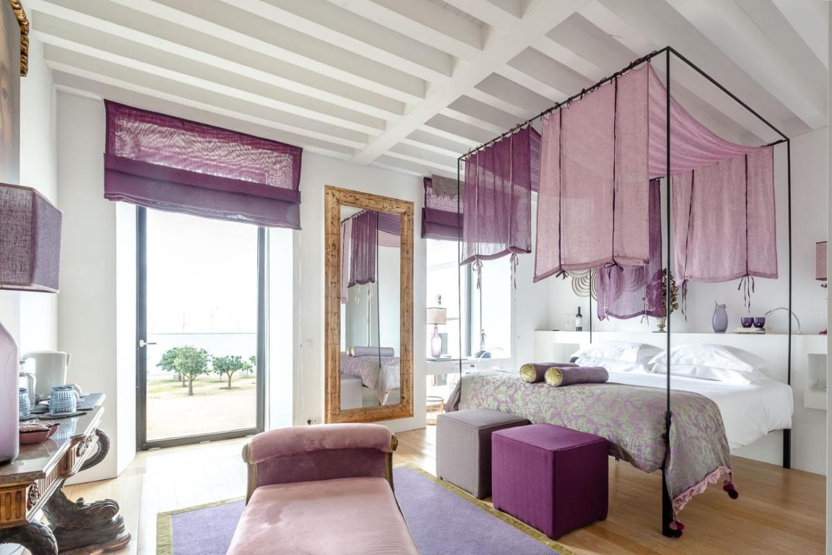 um quarto com uma cama grande e cortinas cor-de-rosa em Torre de Palma Wine Hotel, Monforte, a Member of Design Hotels em Monforte mais 86 fotografias