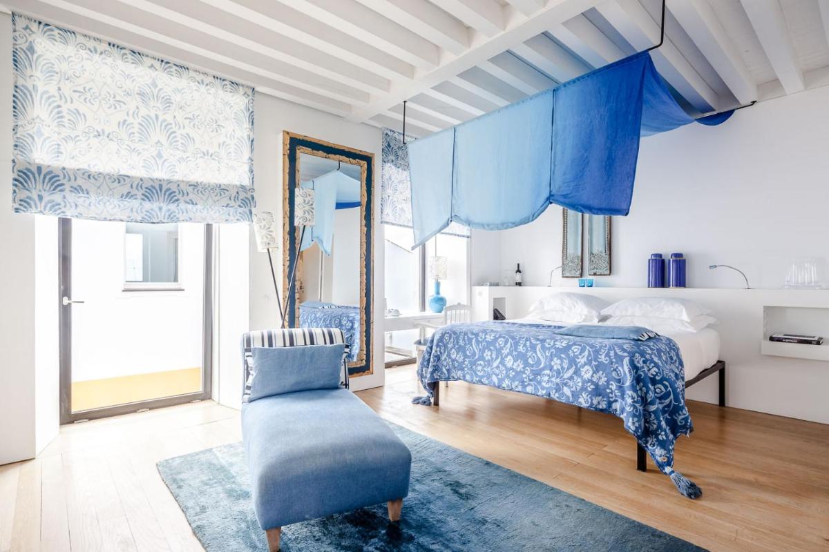 um quarto com cortinas azuis e uma cama e uma cadeira em Torre de Palma Wine Hotel, Monforte, a Member of Design Hotels em Monforte