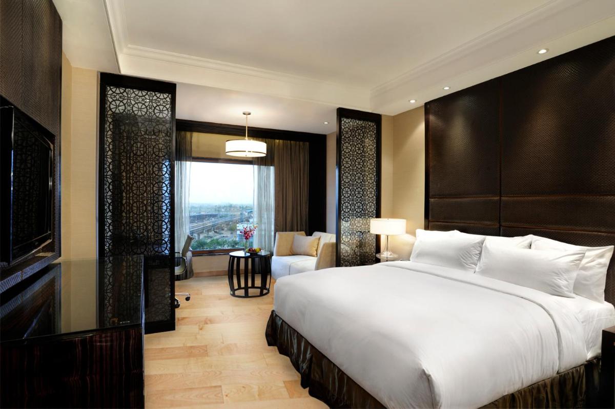 a bedroom with a large bed and a living room at Crowne Plaza New Delhi Mayur Vihar Noida by IHG in New Delhi