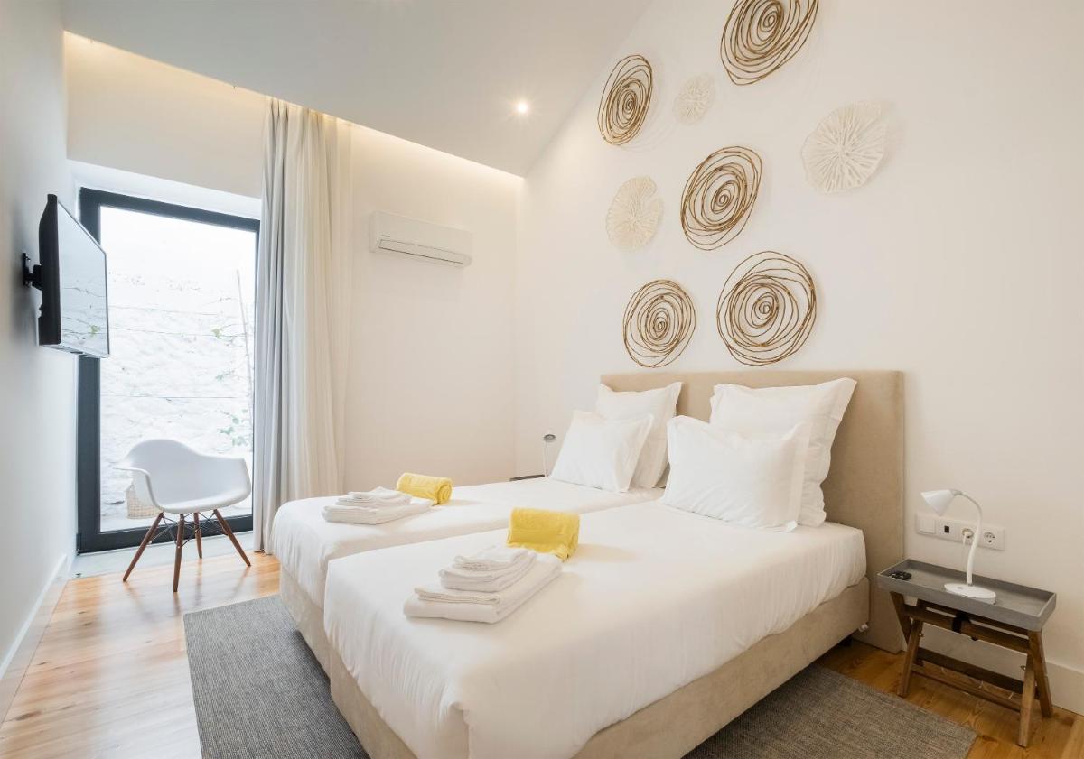 um quarto branco com uma cama branca e uma janela em Aqua - Pópulo Eco Village em Ponta Delgada
