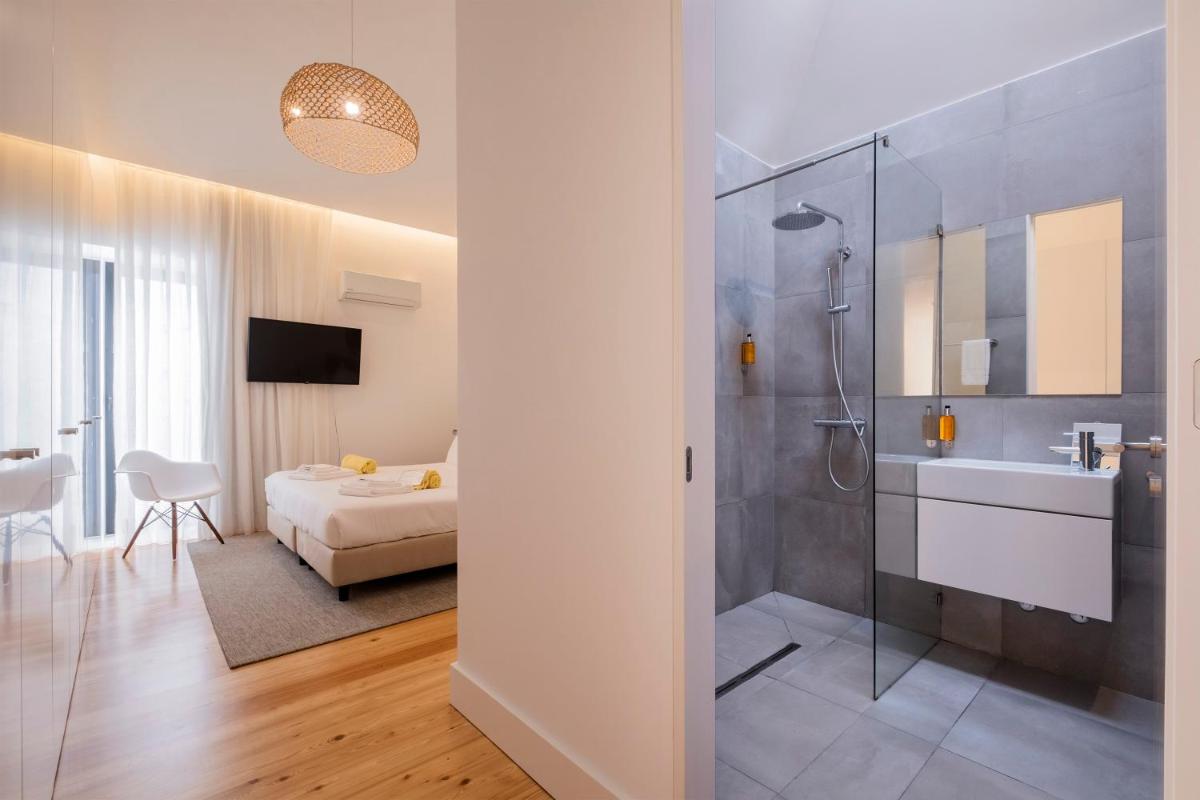 um banheiro com chuveiro, pia e cama em Aqua - Pópulo Eco Village em Ponta Delgada