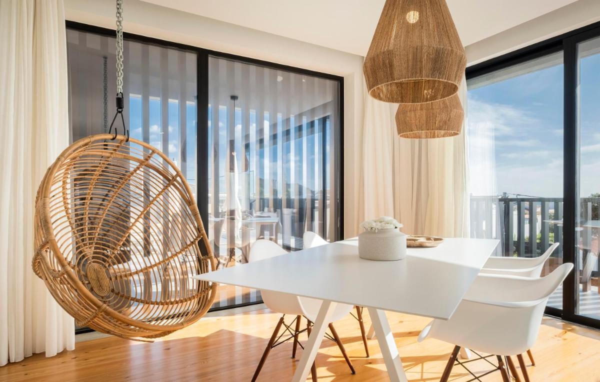 uma sala de jantar com uma mesa branca e uma cadeira de vime em Aqua - Pópulo Eco Village em Ponta Delgada