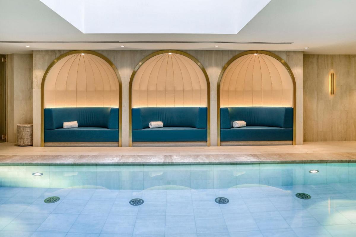 une piscine d'hôtel avec des canapés bleus et une piscine dans l'établissement Maison Albar - Le Vendome, à Paris