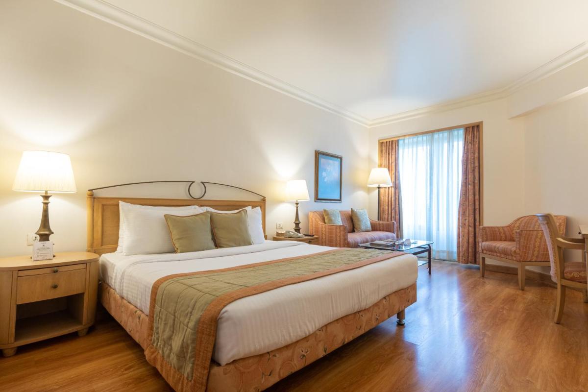 a hotel room with a large bed and a chair at The Orchid Hotel Mumbai Vile Parle in Mumbai