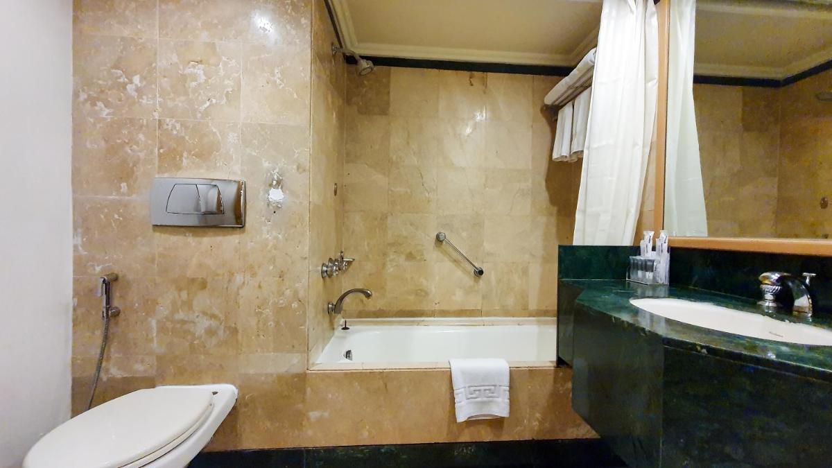 a bathroom with a tub and a toilet and a sink at The Orchid Hotel Mumbai Vile Parle in Mumbai